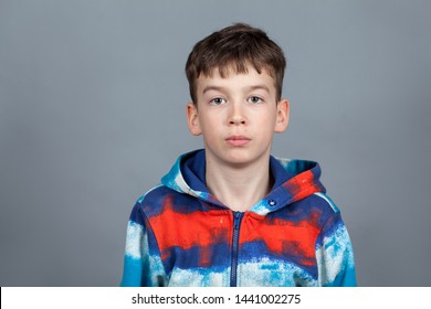 Portrait Of A Serious Teenager In A Colored Sweater On A Gray Background