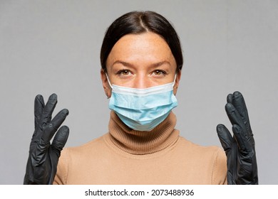 Portrait Of A Serious Woman 35-40 Years Old In A Medical Mask And Gloves On A Gray Neutral Background. Concept: Protection During The Epidemic, Personal Safety.