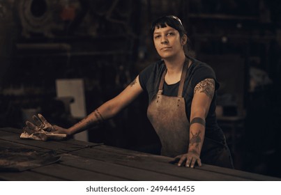 Portrait, serious and woman in dark, factory and proud of gender equality in foundry and blacksmith. Hardworking, apron and manufacturing in workshop, person and skills for welding and employee - Powered by Shutterstock