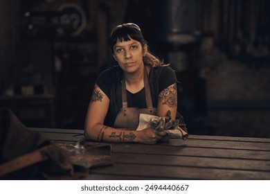 Portrait, serious and woman in dark, workshop and proud of gender equality in foundry and blacksmith. Hardworking, apron and manufacturing in factory, person and skills for welding and employee - Powered by Shutterstock