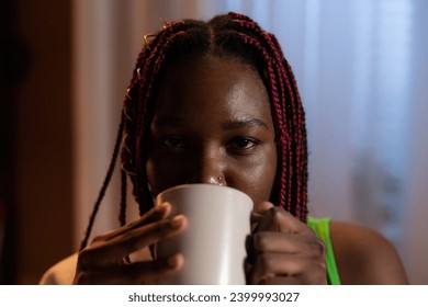 Portrait of serious woman holding coffee near facesmiling sniffing looking at camera tastying freshly gorund coffee.