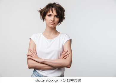 Portrait Of Serious Woman With Short Brown Hair In Basic T-shirt Frowning And Looking At Camera Isolated Over White Background