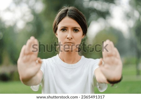 Portrait of serious woman training, practicing wushu in park and looking at camera. Healthy lifestyle, kungfu, martial arts concept
