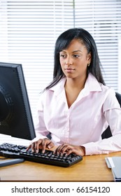 Portrait Of Serious Young Black Business Woman At Desk Typing On Computer