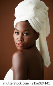 Portrait Of Serious Young Black Woman With Towel On Head Looking Over Shoulder At Camera