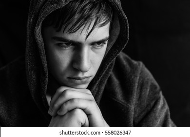 Portrait of serious young man on black background, teenager in studio, close up, monochrome