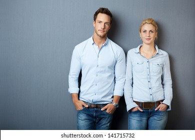 Portrait Of A Serious Young Man And Woman Looking In Camera And Standing Against Gray Background