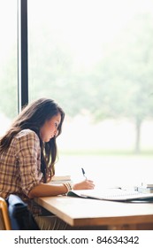 Portrait Of A Serious Young Student Writing An Essay In A Library