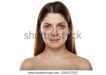 Portrait of a serious young woman with no make up standing on a white background in studio.