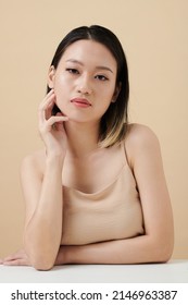 Portrait Of Serious Young Woman Touching Face And Looking At Camera