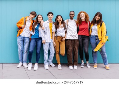 Portrait of seven young student friends leaning on blue wall. Diverse teenage classmates looking at camera standing at university campus. Education and youth concept. - Powered by Shutterstock