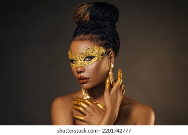 Portrait Sexy African Woman Face Close Up In Golden Venetian Carnival Mask. Girl Afro Fashion Model Perfect Skin, Golden Evening Makeup, Glitter Diamond Stones Lip Gloss, Hands In Gold Liquid Paint