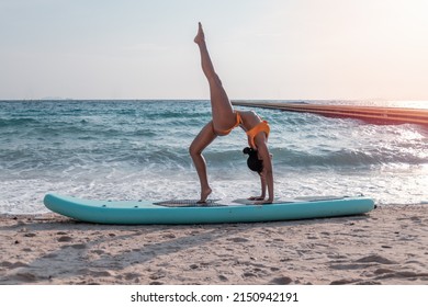 Portrait sexy beautiful Asian model wearing bikini swimming suite posing yoga practice happy on beach with sup board is water sport game and hobby leisure in summer holiday lifestyle.