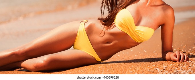 Portrait sexy beautiful brunette hair woman, has yellow bikini, slim tan gold body. Posing in tropical hot sea. Luxury resort. Travel lifestyle. Nature sunny day. Epilation