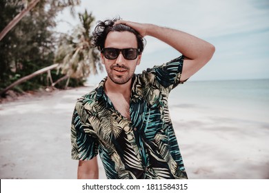 Portrait Of Sexy Latino Brunet Man In Hawaiian Shirt And Sunglasses On Tropical Beach. Men's Fashion And Beauty In Travel And Vacation