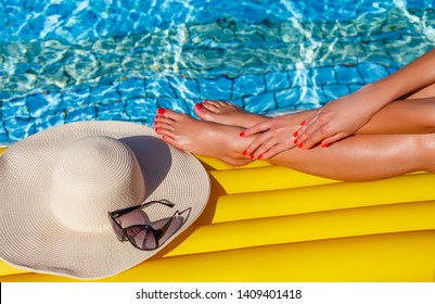 Portrait Of Sexy Tanned Slim Model Woman In Colorful Bikini And Hat Having Relax And Enjoying In Swimming Pool. Creative Gel Polish Red Pedicure And Manicure. Luxury Travel Tropical Resort Concept