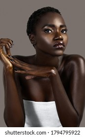 A Portrait Of A Sexy Young Black Female With Short Black Hair, Moist Lips, Perfectly Manicured Nails Wearing A White Wrap Sitting In Front Of A Gray Background.