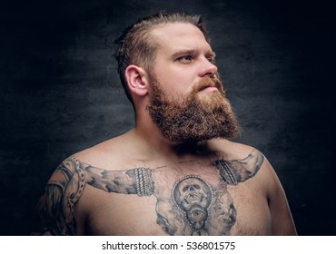 Portrait of a shirtless bearded male with tattooed arm and bull tattoo on a chest.