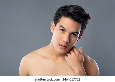 Portrait of shirtless young asian handsome man touching face for skin care and beauty concepts against gray studio background