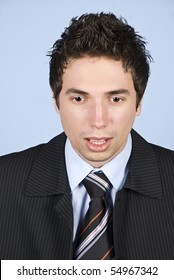 Portrait of shocked business man looking down in front of blue background