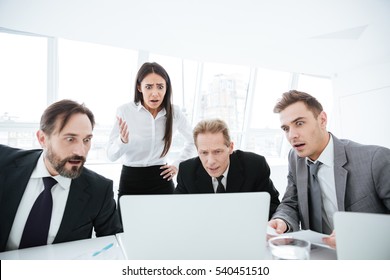 Portrait Of Shocked Business Team By The Table Looking At Laptop In Office