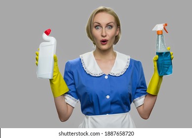 Portrait Of Shocked House Maid Looking At Camera. Happy Surprised House Maid Posing With Cleaning Supplies Against Gray Background.