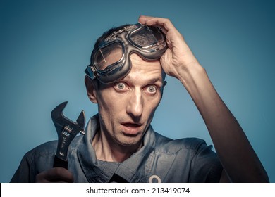 Portrait of shocked locksmith with the adjustable wrench.