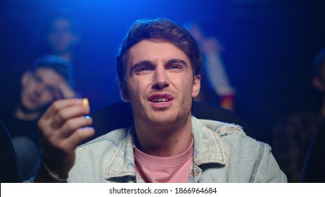 Portrait of shocked man watching bad film in movie theater. Irritated guy talking himself during boring movie in dark hall. Closeup upset male person eating popcorn in cinema. - Powered by Shutterstock