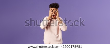 Portrait of shocked, startled handsome man being embarrassed and scared of seeing something unappropriate and awkward, cover eyes but peeking through fingers from interest Stockfoto © 