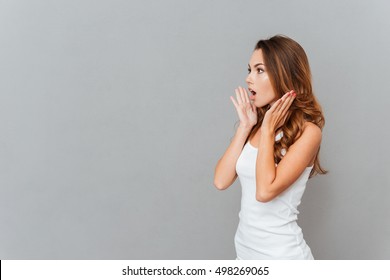 Portrait Of Shocked Woman With Mouth Open Looking Away Isolated On A Gray Background