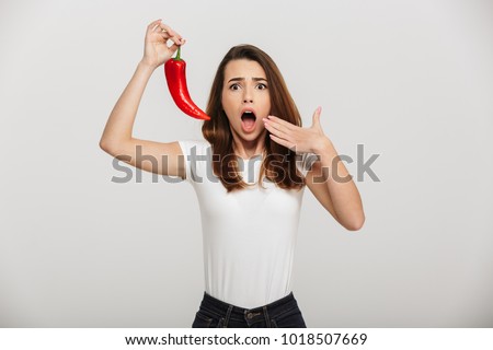 Portrait of a shocked young woman tasted chili pepper isolated over white background