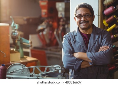 Portrait of shoemaker standing with arms crossed in workshop - Powered by Shutterstock