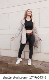 Portrait shooting of a stylish girl. Beige shades. Trends of spring and summer 2020.Black pants and black top. Beige trench coat.