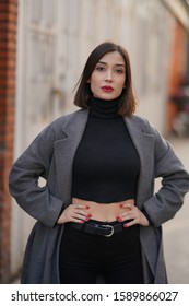 portrait of short hair girl in grey coat, black blouse, long leather boot and black pants in the street - Shutterstock ID 1589866027