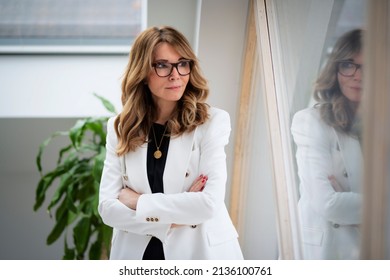 Portrait shot of an attractive middle aged woman looking out the windoe and smiling while standing at the window.  - Powered by Shutterstock