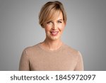 Portrait shot of beautiful blond woman looking at camera and smiling while standing at isolated grey background.