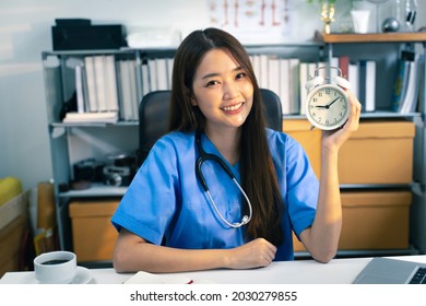 Portrait Shot Of Female Doctor With Office Clock In Doctor’s Office.