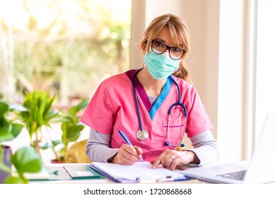 Porträtaufnahme von Ärztin mit Gesichtsmaske zur Vorbeugung während der Arbeit auf Laptop im Büro des Arztes.