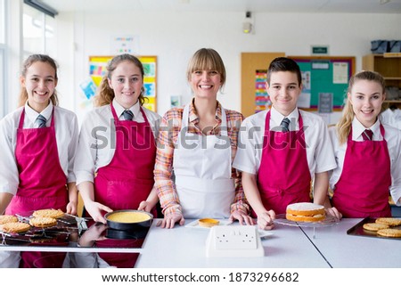 Portrait shot a home economics teacher and her students with desserts in the kitchen classroom.