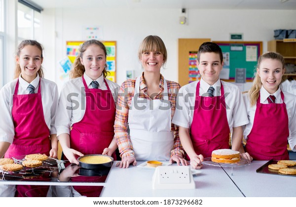 Portrait shot a home economics teacher\
and her students with desserts in the kitchen\
classroom.