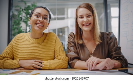 Portrait Shot From Laptop Camera Of Two Diverse Project Managers Making Video Call In Creative Office Environment. Happy Female Caucasian And Latin Specialists Listening To Colleague Over Live Camera.