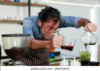 Portrait Shot Professional Asian Man Barista With Glasses Concentrate Mix Coffee And Tea By Filled Cup With Ice At Bar Counter. The Ways To Brewing Coffee. Coffee Shop Barista Cafe Concept.