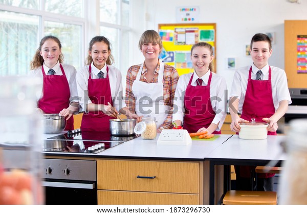 Portrait shot of a teacher and high\
school students cooking in a home economics\
class.