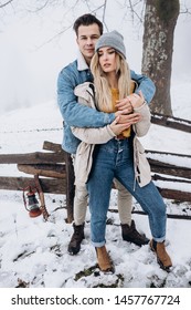 Portrait shot of the young attractive stylish Caucasian boyfriend and girlfriend standing in hugs and posing to the camera in winter outside.