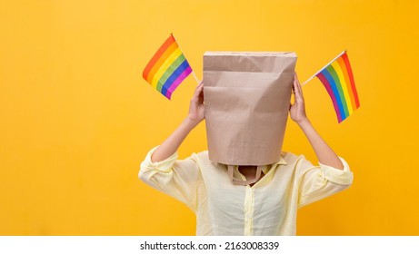 Portrait Of Shy LGBTQ People Covering Her Face Waving Rainbow Flag For Coming Out Of The Closet In Pride Month To Promote Marriage Equality And Differences Of Homosexual And Discrimination