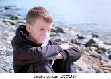 Portrait Sick 8y Child Boy Uses Nebulizer Sits On Seaside. Inhaling Inhaler Mask. Fibrosis Cystic Copd And Treatment. Asthma Pulmonary Respiratory Breath Problem Cure. Painkiller Sedative Gas Oxygen.