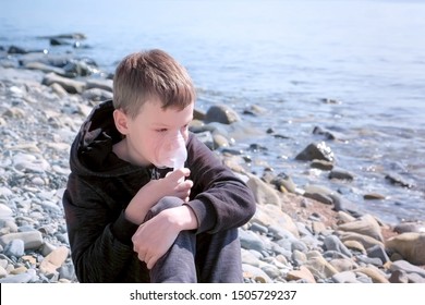 Portrait Sick 8y Child Boy Uses Nebulizer Sits On Seaside. Inhaling Inhaler Mask. Fibrosis Cystic Copd And Treatment. Asthma Pulmonary Respiratory Breath Problem Cure. Painkiller Sedative Gas Oxygen.