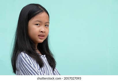 Portrait Of Side View Of Kid Asian Girl Shy And Smiling On Blank Green Screen