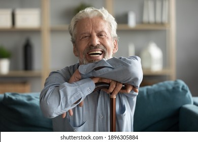 Portrait of sincere smiling older senior man with wooden walking cane resting on comfortable sofa, feeling joyful at home. Happy overjoyed retired disabled mature grandfather looking at camera. - Shutterstock ID 1896305884