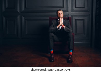 Portrait of sitting businessman in strict gray suit and colorful multi colored socks. Business and success concept. - Powered by Shutterstock